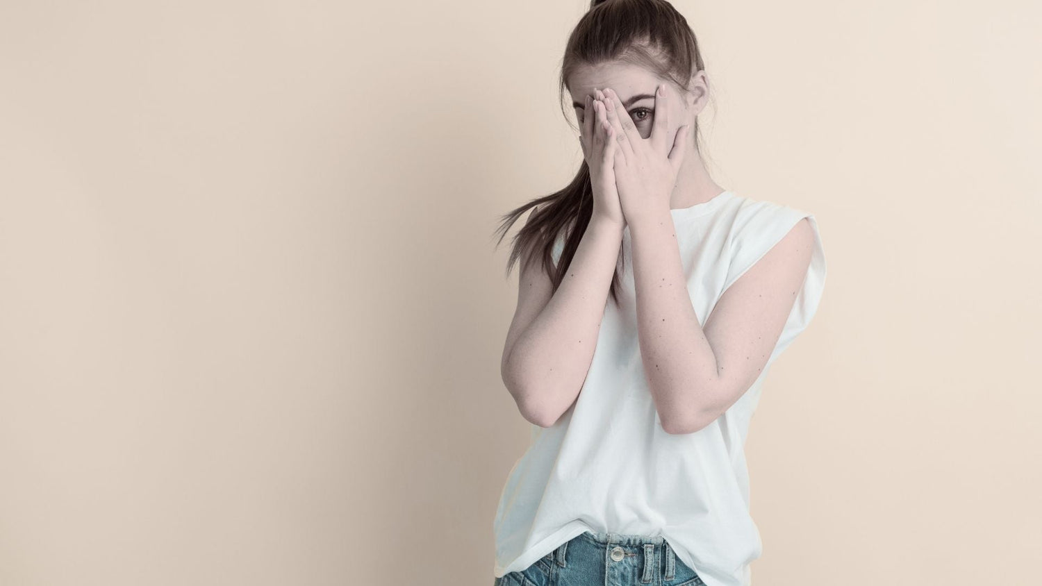 Tween girl covering face with hands - ingredients tween skincare routines should not be using