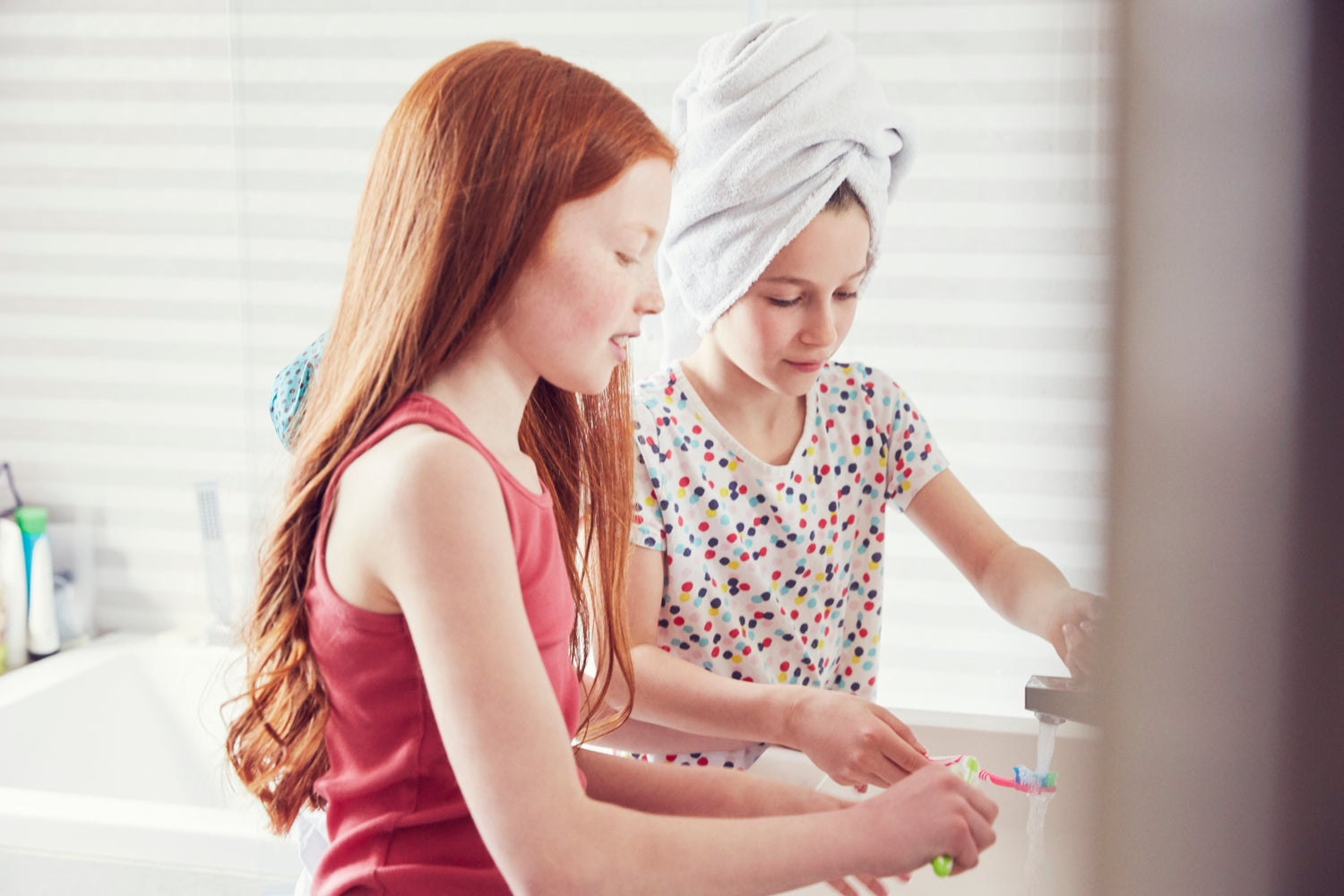 Tween girls doing skincare routine in bathroom